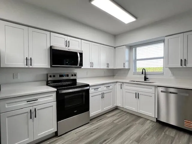 a kitchen with stainless steel appliances white cabinets a sink and a stove