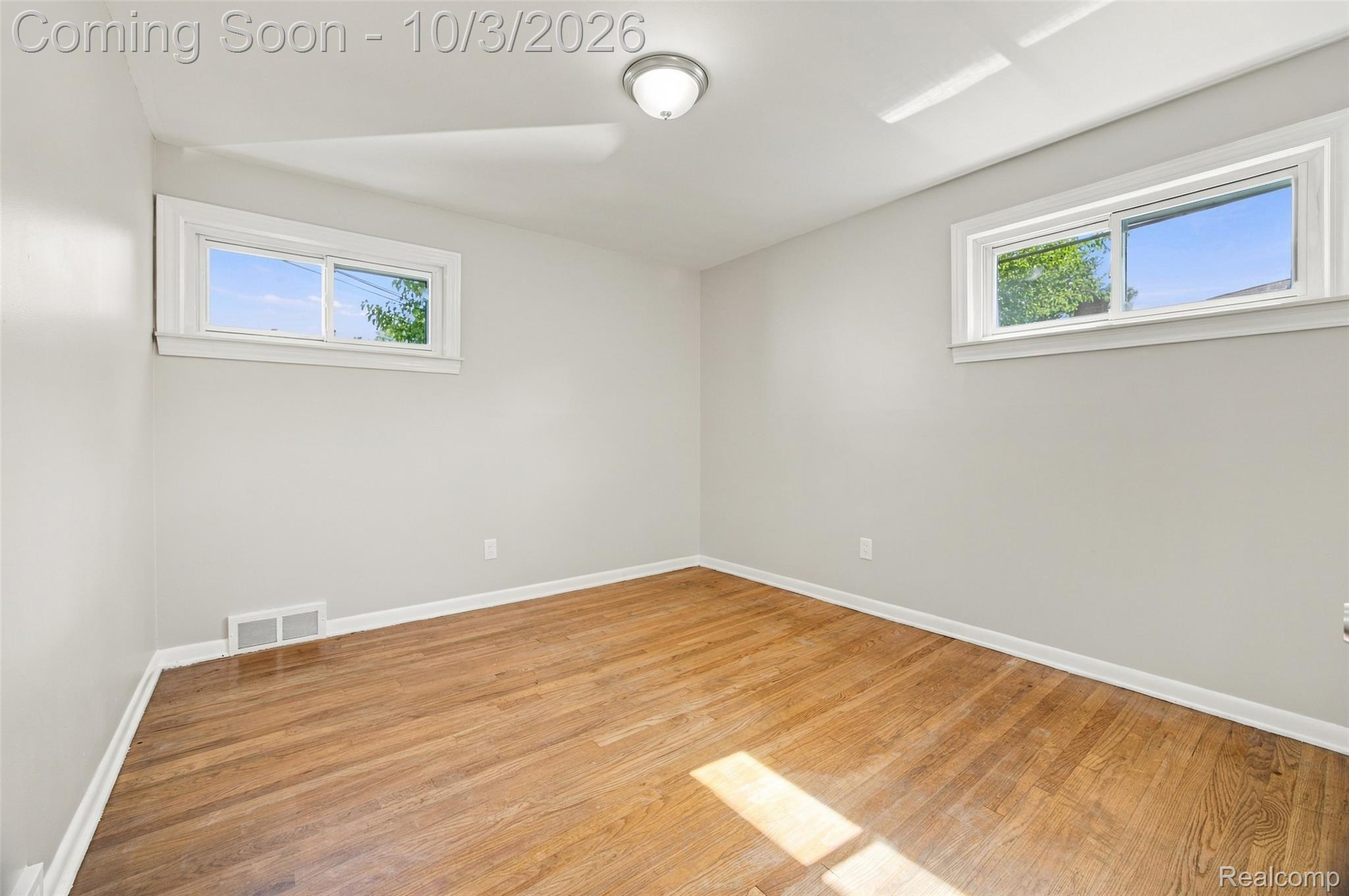 556 Henry Ruff Road Garden City, MI 48135 - Photo 17 of 49 Hardwood flooring, light gray wall finishes, white trim, two clear-pane windows, and a flush-mount ceiling light fixture