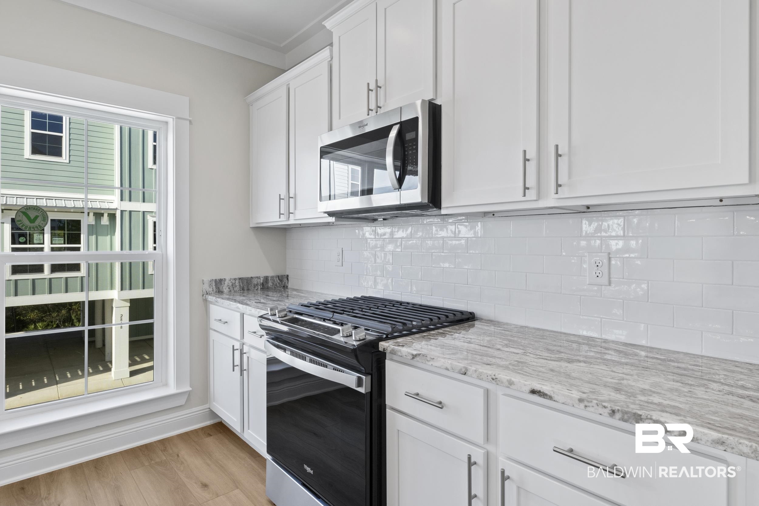 2847 Salt Drive Orange Beach, AL 36561 - Photo 13 of 29 Kitchen with white cabinetry, light stone counters, light hardwood / wood-style floors, decorative backsplash, and appliances with stainless steel finishes