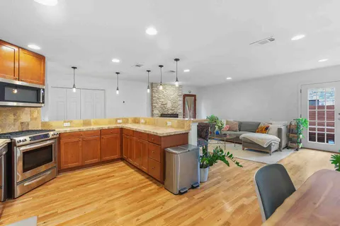 a large kitchen with stainless steel appliances granite countertop a lot of cabinets and wooden floor