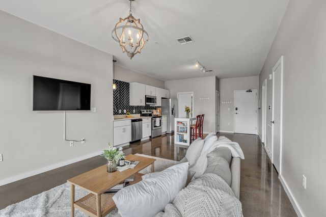a living room with furniture a flat screen tv and kitchen view