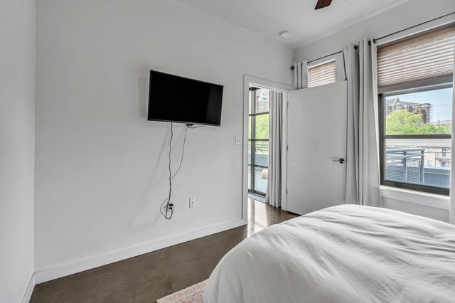 a bedroom with a bed tv and a window