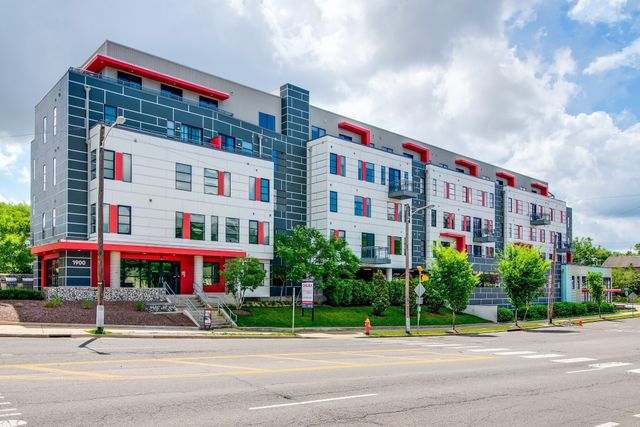 a front view of multi story residential apartment building with yard and traffic signal