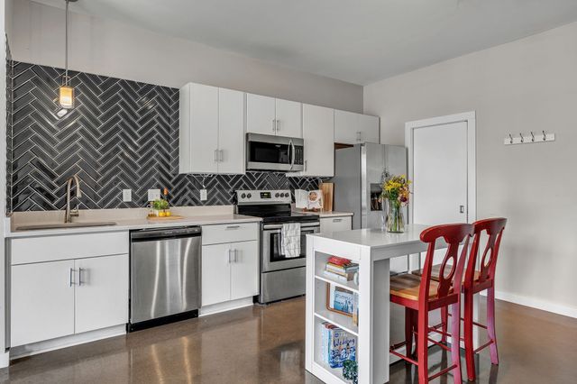 a kitchen with stainless steel appliances a stove a sink a microwave a dining table and chairs