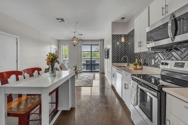 a kitchen with stainless steel appliances granite countertop a stove a sink dishwasher and cabinets with wooden floor