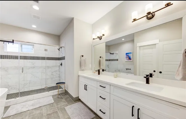 a bathroom with a double vanity sink mirror and shower