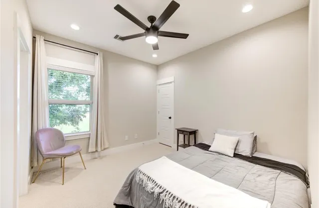 a bedroom with a bed a chair and a large window