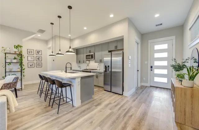 a kitchen with stainless steel appliances kitchen island granite countertop a refrigerator a sink a stove and a wooden floors