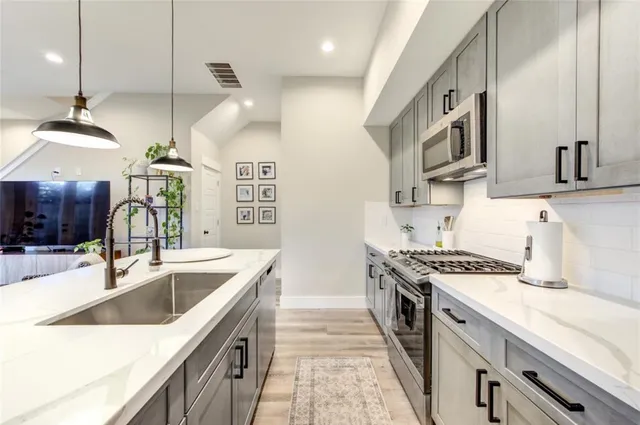 a kitchen with stainless steel appliances granite countertop a sink a stove and a sink