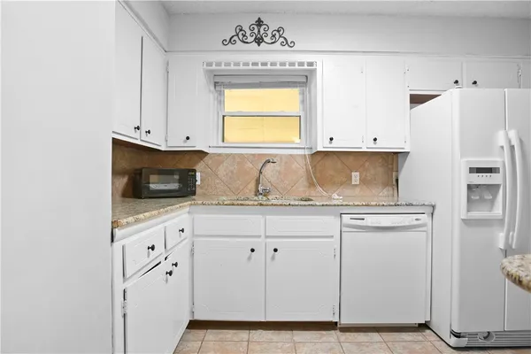 a kitchen with granite countertop white cabinets and white appliances