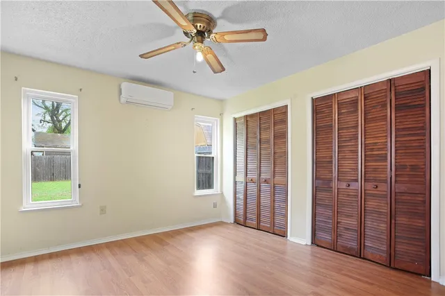 an empty room with wooden floor chandelier fan and windows