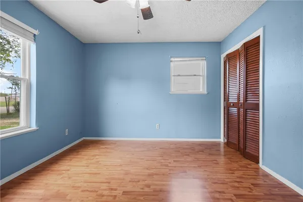 an empty room with wooden floor and windows