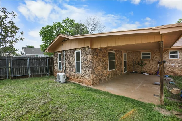 a view of backyard with wooden fence and a large tree