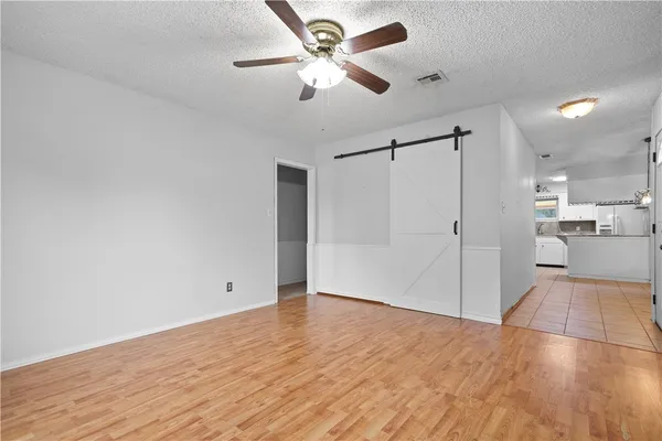 a view of an empty room with wooden floor and a ceiling fan