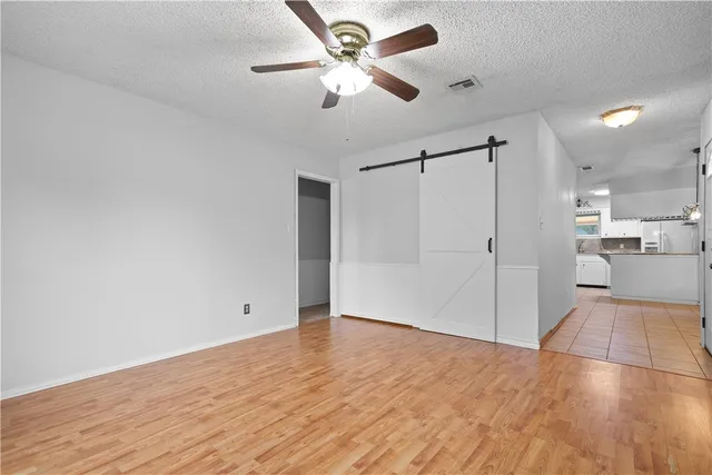 a view of an empty room with wooden floor and a ceiling fan