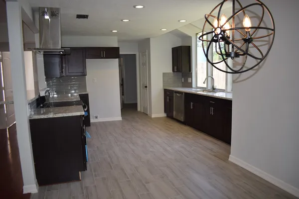 a kitchen with stainless steel appliances granite countertop a refrigerator a sink a stove and a wooden floors