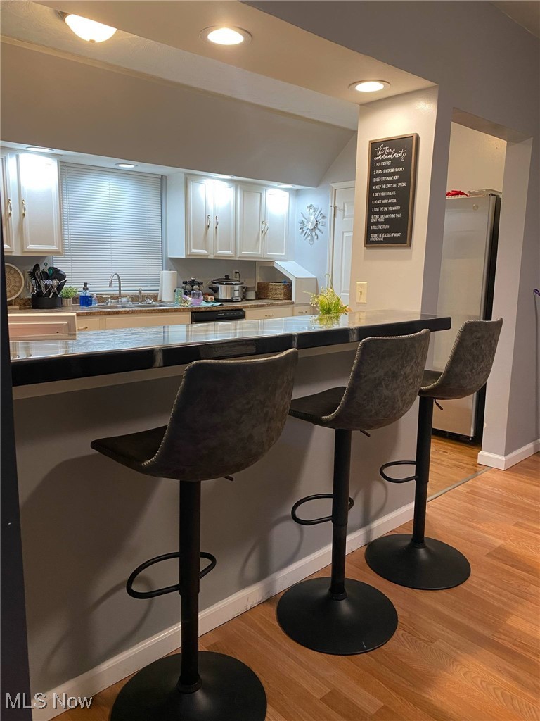 408 Broad State Road Conneaut, OH 44030 - Photo 15 of 39 Bar area featuring white cabinets, light wood-style flooring, freestanding refrigerator, and recessed lighting
