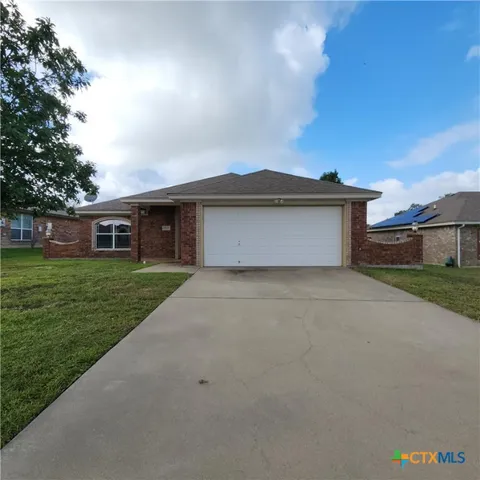 a front view of house with yard and trees in the background