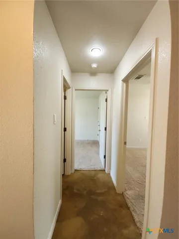 an empty room with windows and chandelier fan