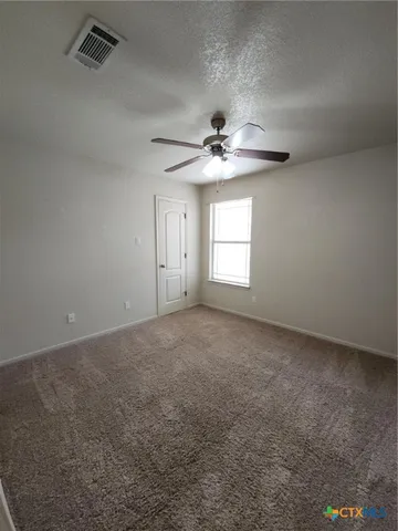 an empty room with windows and fan