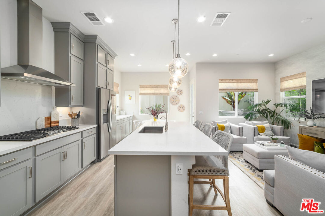 587 Daniel Freeman Circle Inglewood, CA 90301 - Photo 6 of 25 a kitchen with stainless steel appliances kitchen island granite countertop a stove a sink a dining table and chairs with wooden floor