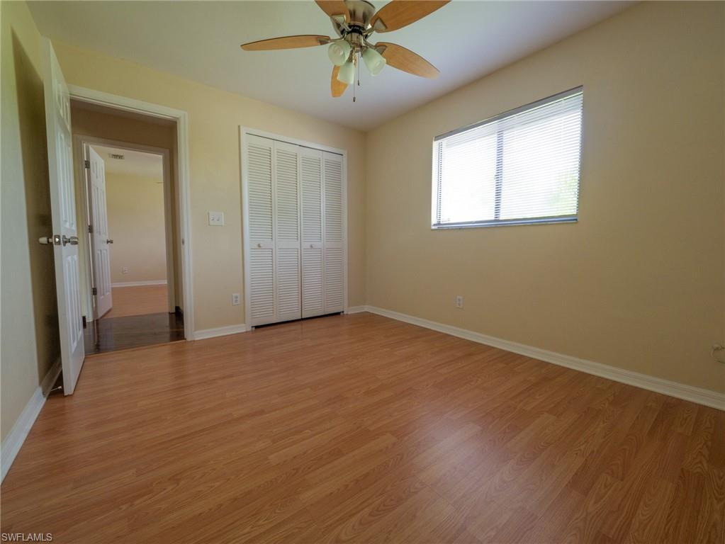18414 Tulip Road Fort Myers, FL 33967 - Photo 29 of 37 Room featuring wood-finish flooring, a ceiling fan with light fixture, louvered bi-fold closet doors, a window with blinds, and light-toned wall paint
