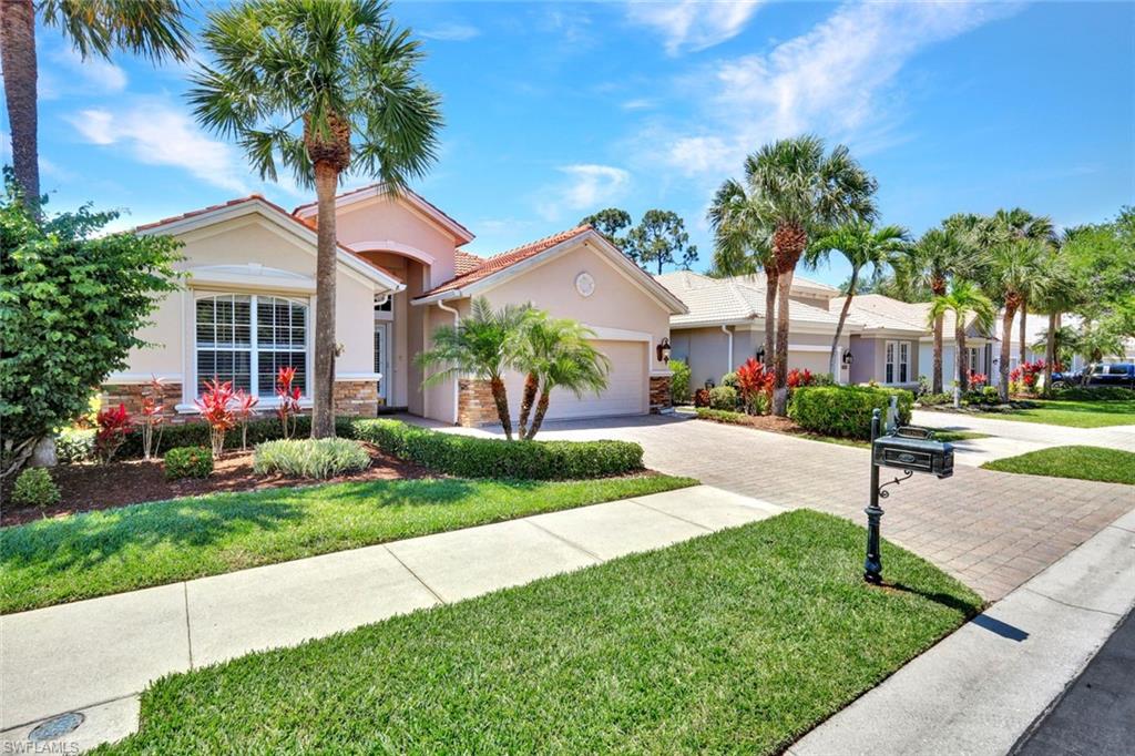 16208 Parque Lane Naples, FL 34110 - Photo 2 of 22 a front view of a house with a yard and potted plants