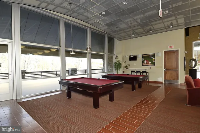 a living room with stainless steel appliances furniture a flat screen tv and a kitchen view