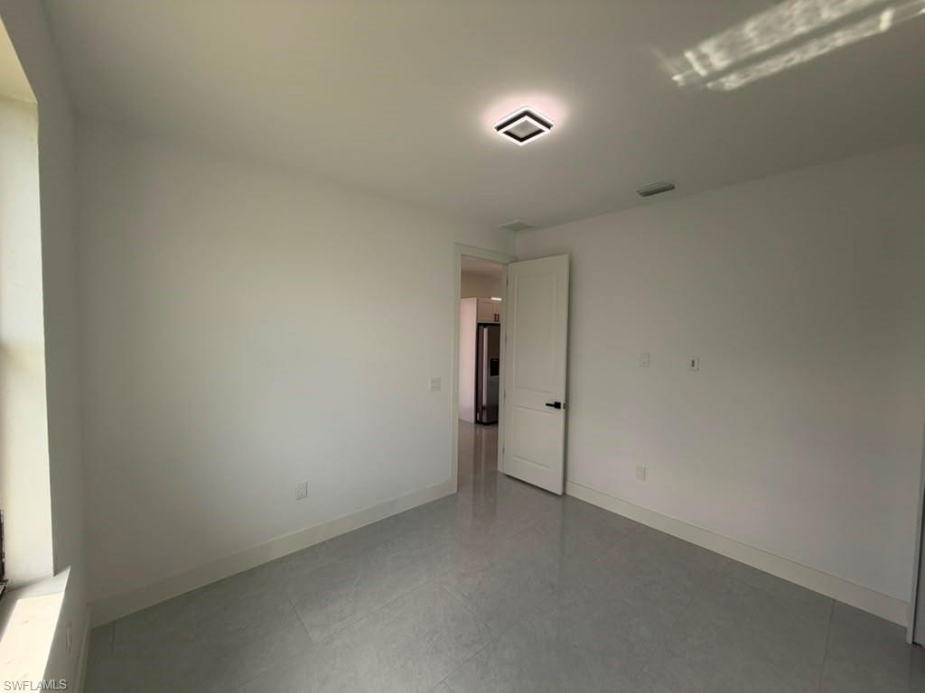 907 Homestead Road South Lehigh Acres, FL 33974 - Photo 41 of 43 Bright room featuring light grey tile flooring, white baseboards, and a modern flush-mount ceiling light