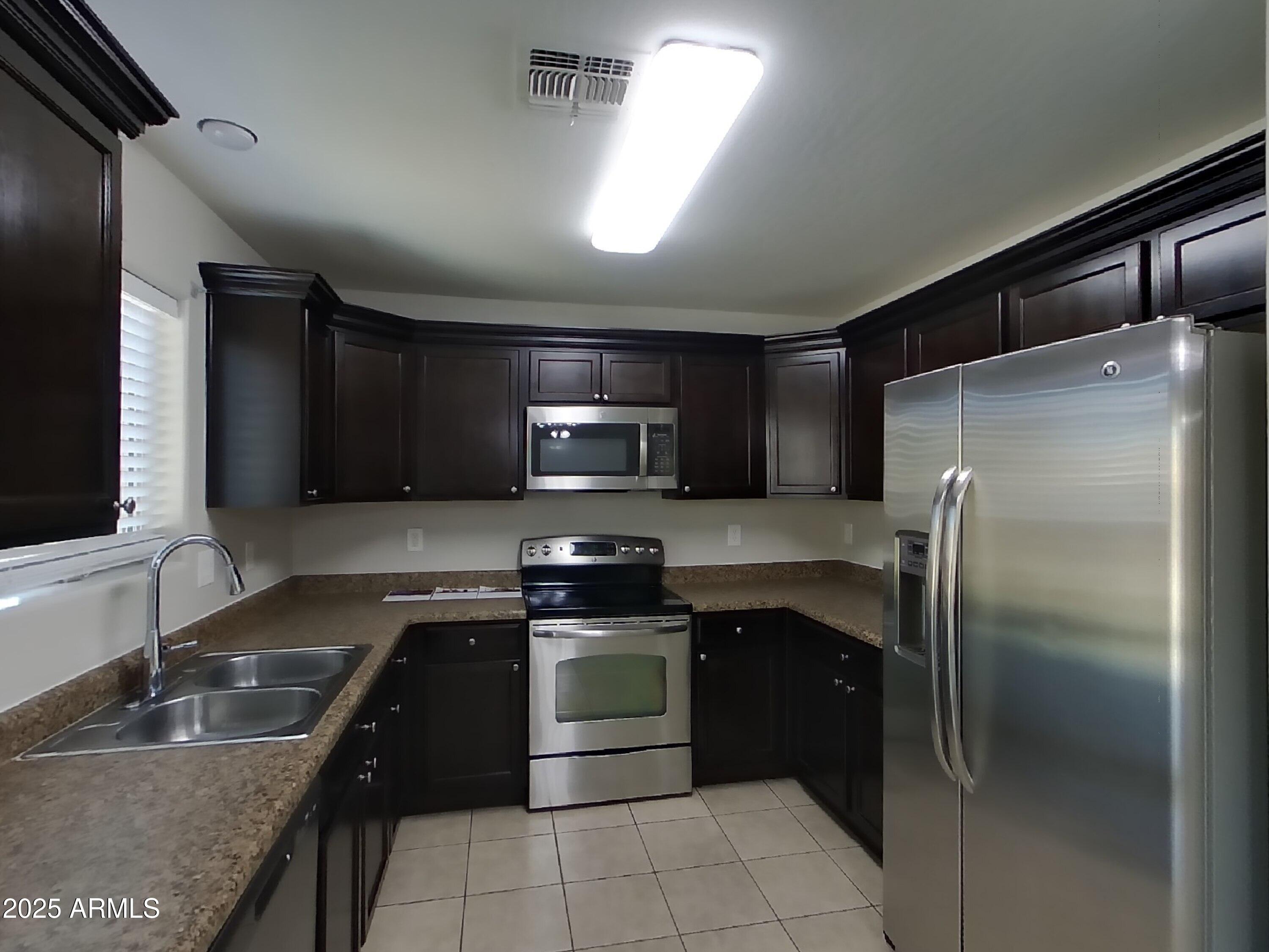 3513 South 89th Avenue Tolleson, AZ 85353 - Photo 5 of 19 a kitchen with stainless steel appliances granite countertop a sink stove microwave and refrigerator