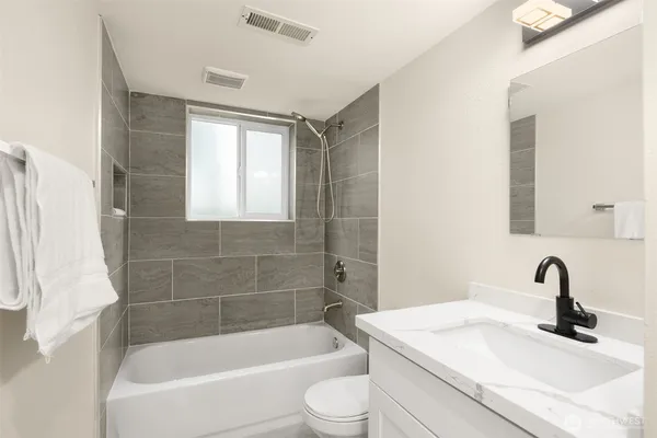 a bathroom with a granite countertop sink toilet and bathtub
