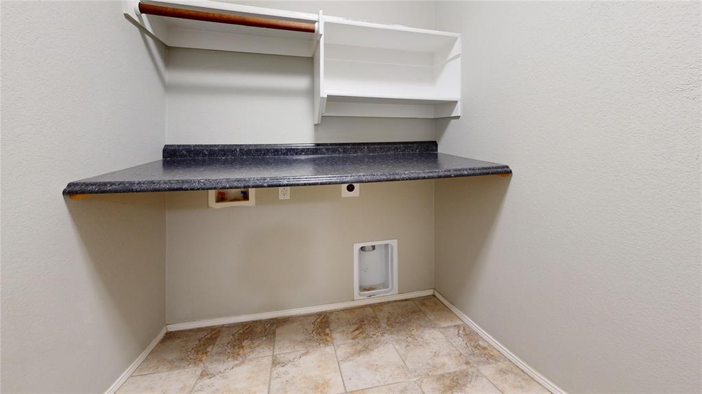 3101 Buckthorn Street Forney, TX 75126 - Photo 30 of 40 Dedicated laundry space featuring a dark speckled countertop, light-toned tiled flooring, wall-mounted shelving, and a garment rod
