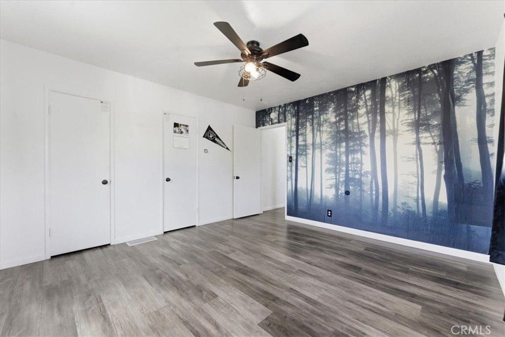 34863 Wildwood Canyon Road Yucaipa, CA 92399 - Photo 10 of 22 a view of an empty room with wooden floor and a ceiling fan