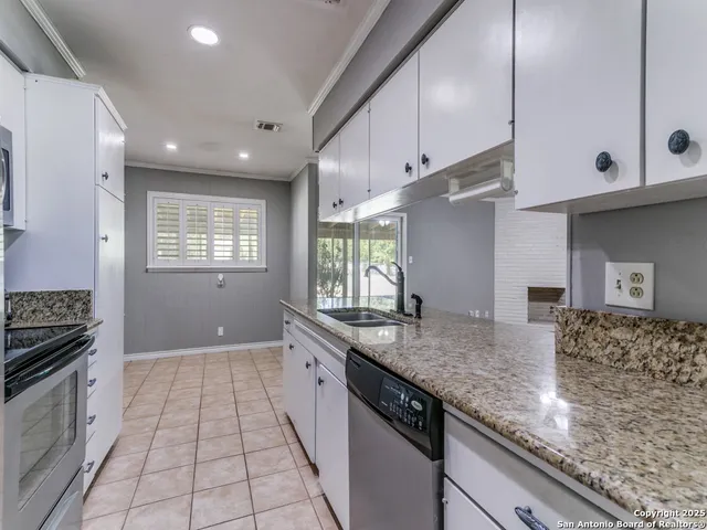 a kitchen with granite countertop a sink stove and cabinets