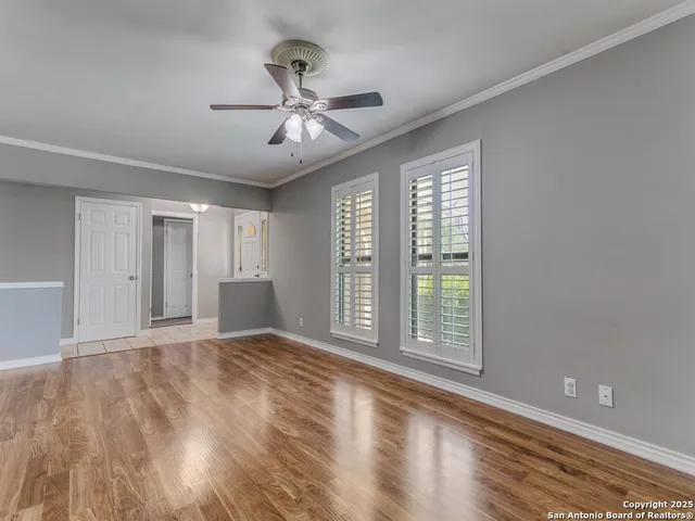 a view of an empty room with a window and wooden floor