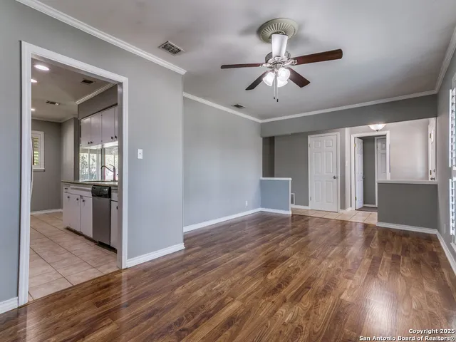 a view of a livingroom with a ceiling fan & kitchen space with wooden floor