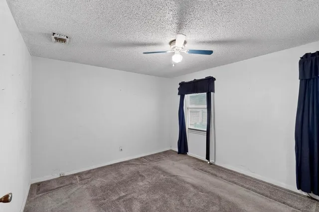 an empty room with a chandelier fan and windows