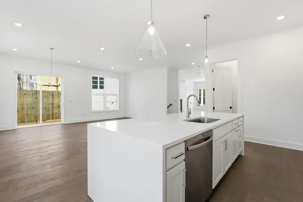 a large kitchen with stainless steel appliances a large counter top a sink a refrigerator and a window