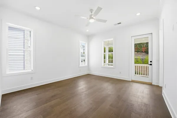 an empty room with wooden floor and windows