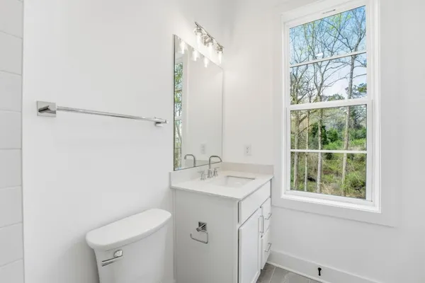 a bathroom with a sink toilet vanity and window