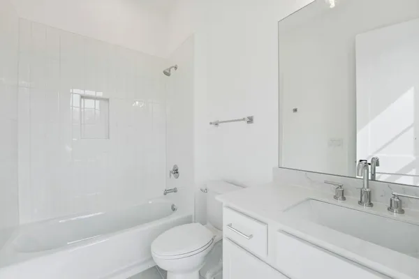 a bathroom with a bathtub shower sink vanity mirror and toilet