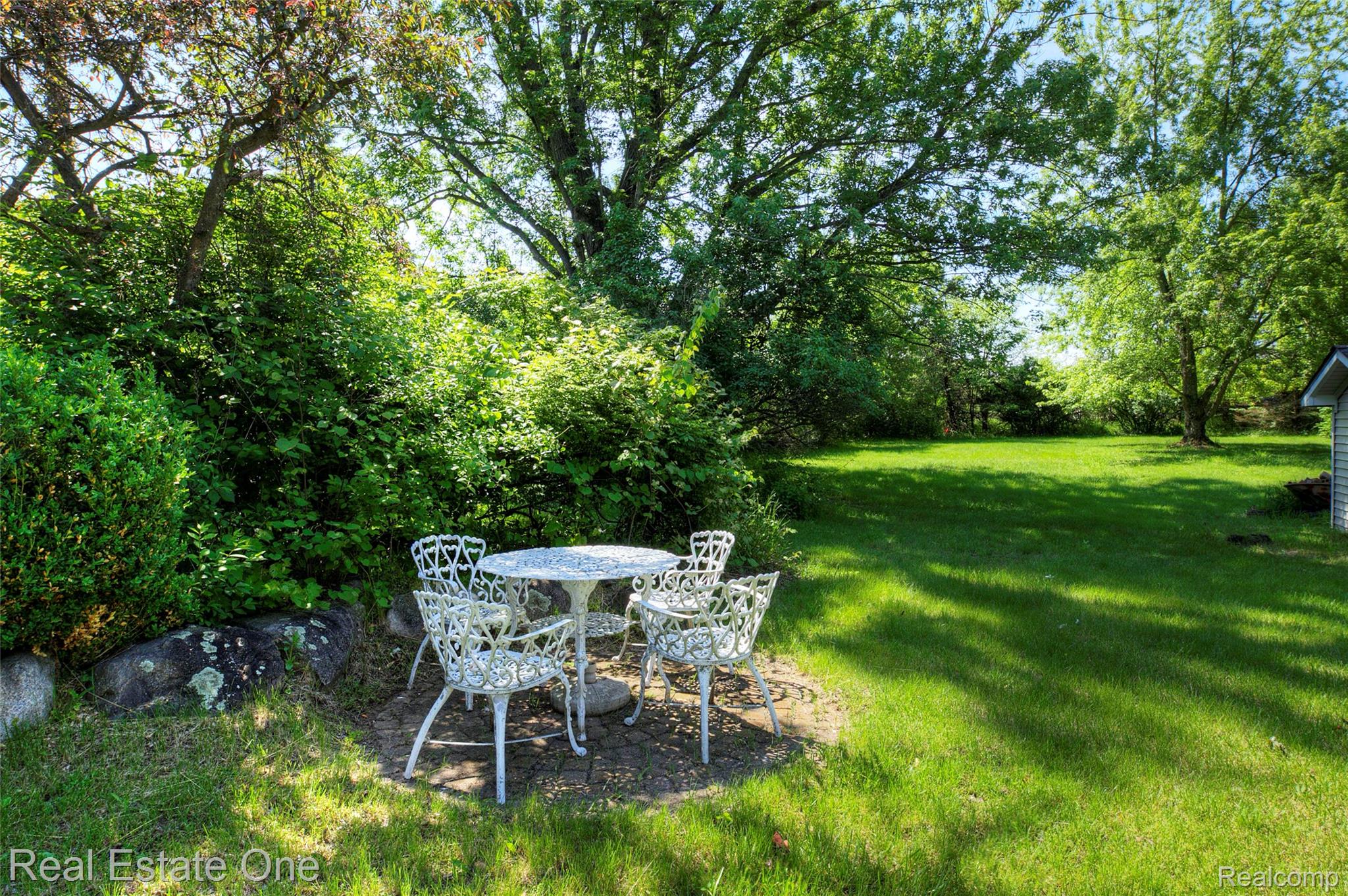 3125 West Commerce Road Milford, MI 48380 - Photo 52 of 63 Expansive backyard featuring a lush lawn, mature trees, and a shaded patio area