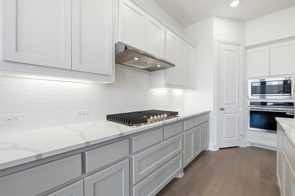 4107 Windy Point Court Oak Point, TX 75068 - Photo 4 of 30 a kitchen with white cabinets and appliances