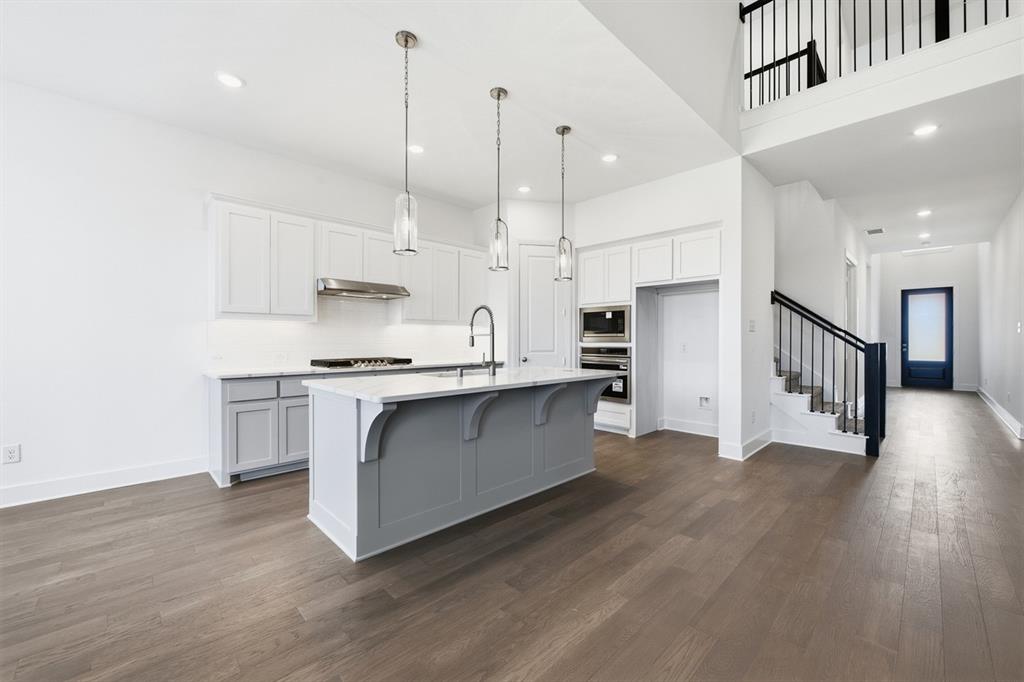 4107 Windy Point Court Oak Point, TX 75068 - Photo 6 of 30 a kitchen with stainless steel appliances kitchen island wooden floors and white cabinets