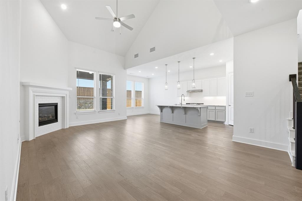 4107 Windy Point Court Oak Point, TX 75068 - Photo 7 of 30 an empty room with wooden floor kitchen view and a fireplace