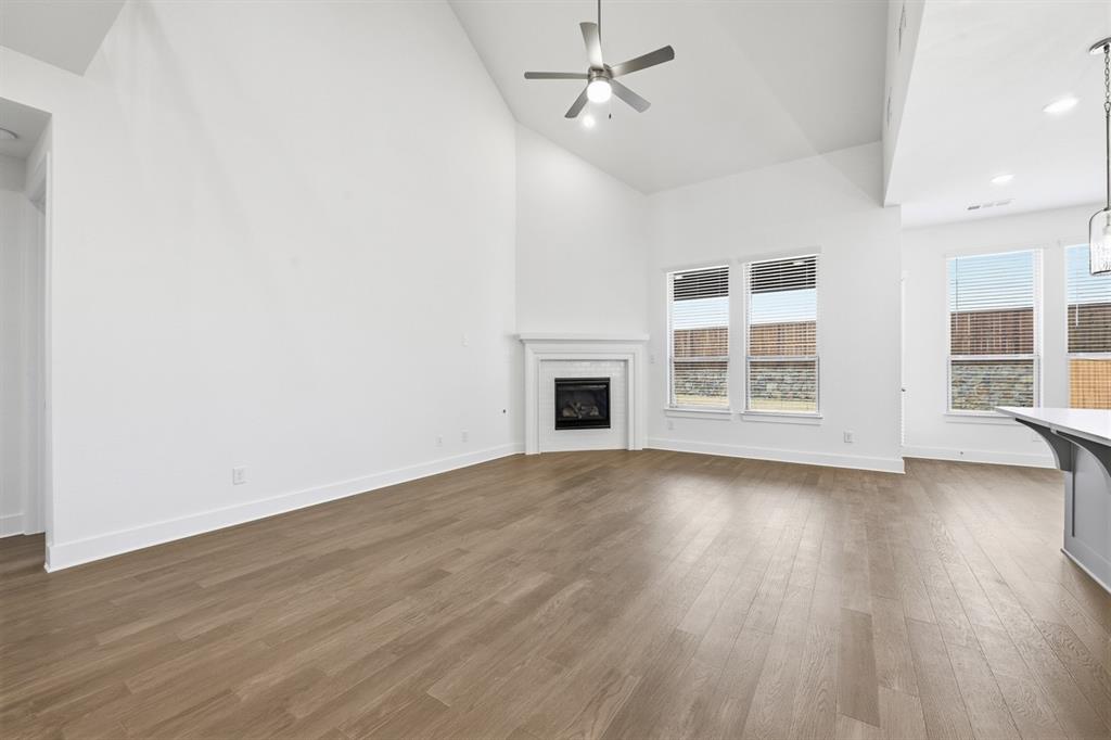 4107 Windy Point Court Oak Point, TX 75068 - Photo 8 of 30 an empty room with wooden floor fireplace and windows