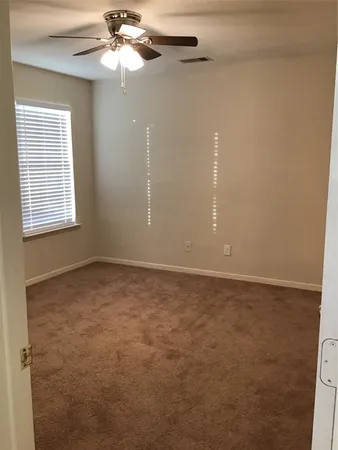 an empty room with a window and a fan