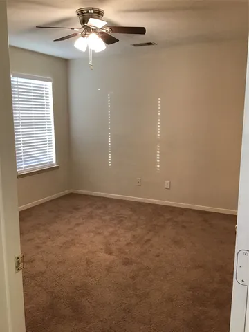 an empty room with a window and a fan