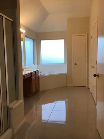 a view of an empty room with window and a kitchen