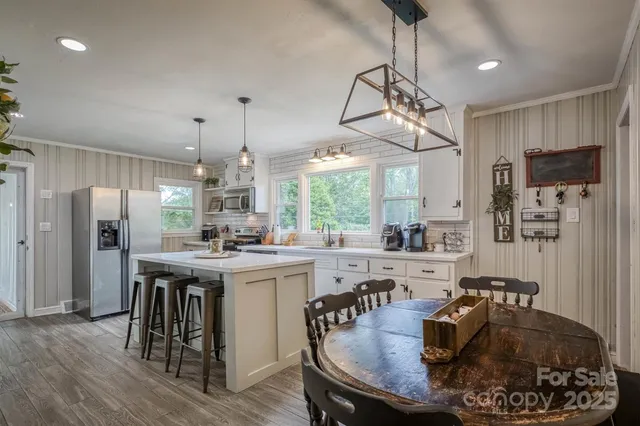 a kitchen with stainless steel appliances granite countertop a stove a refrigerator a kitchen island a dining table and chairs